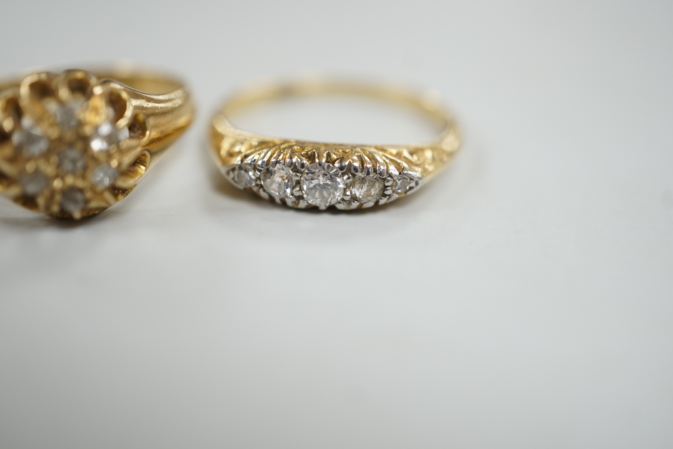 Two early 20th century 18ct and diamond cluster set rings, including graduated five stone, sizes M, gross weight 6.2 grams.